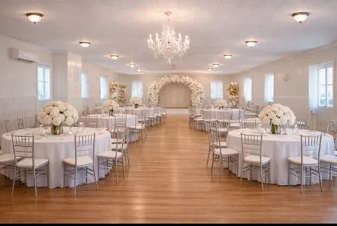 Elegant event hall decorated for birthday party and pink baby shower with round tables and floral arch